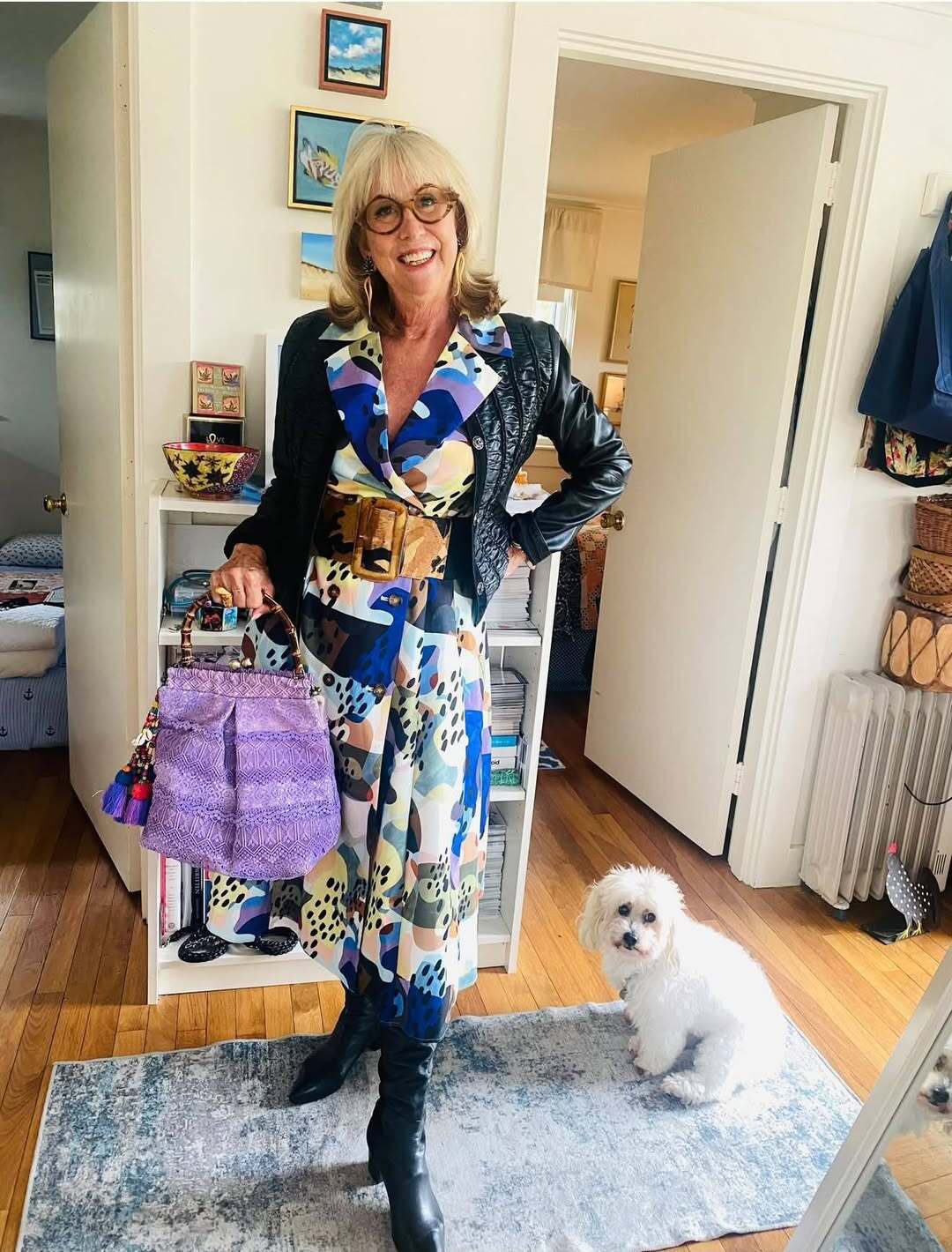 Bonnie Roseman at home with her dog, in a printed dress and leather jacket